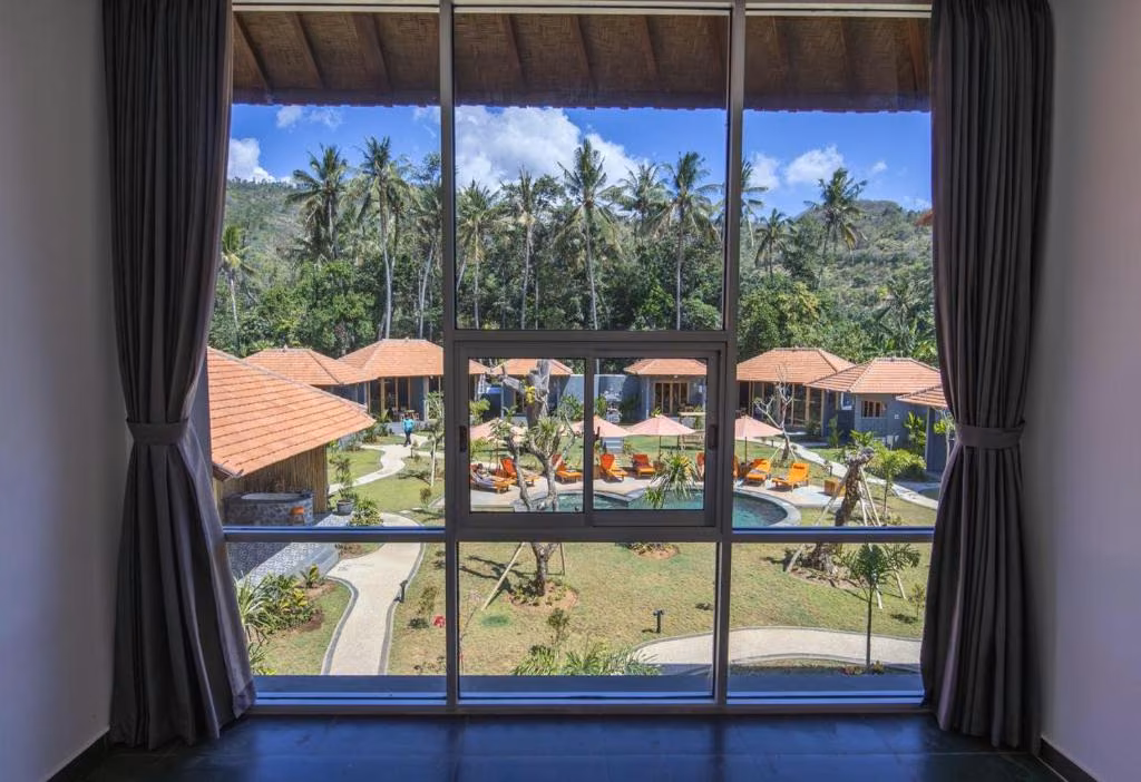 View over the bungalows, palm trees and pool of Aqua Dive Resort in Amed, Bali